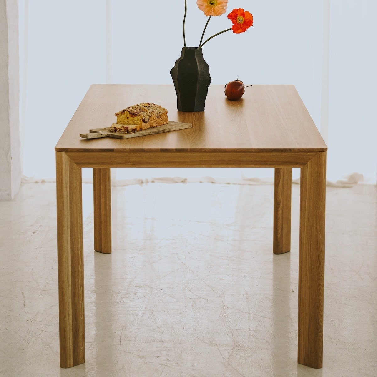 Side view of LUVIO dining table with subtly curved solid oak legs