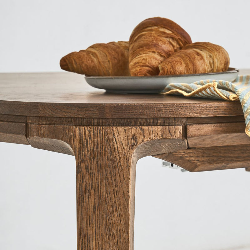 Side view of SEVA table highlighting curved legs and smooth oak finish