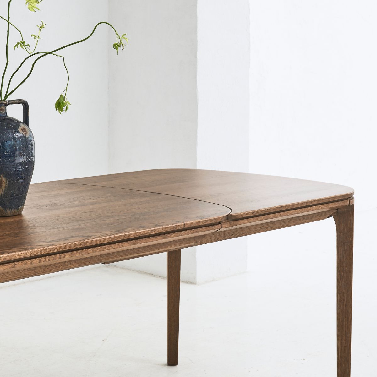 Side view of SEVA table highlighting curved legs and smooth oak finish